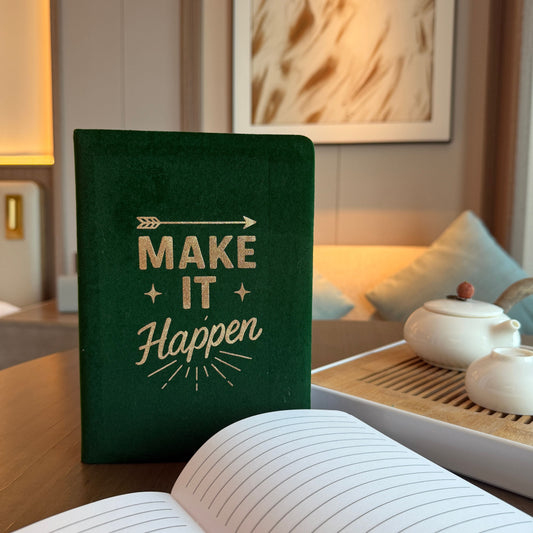 Alt Tag: Dark Green Velvet Notebook – 80 Pages with "Make It Happen" silver embossing, velvet cover, open lined pages on desk