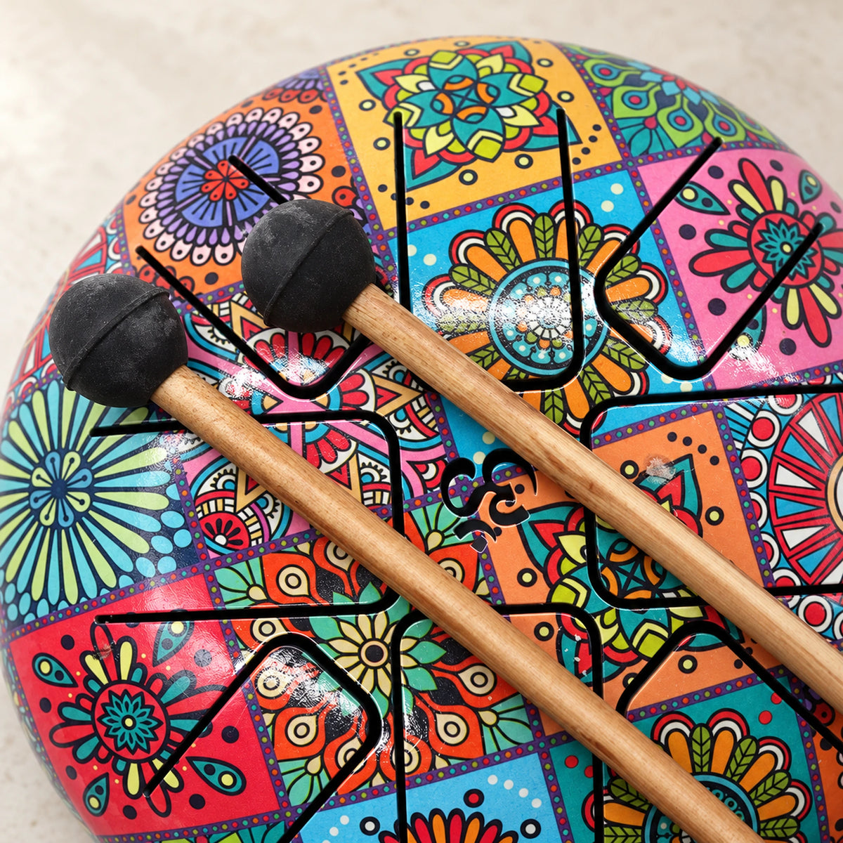 Two black mallet heads with visible seams and wooden shafts rest diagonally across the colourful drum.