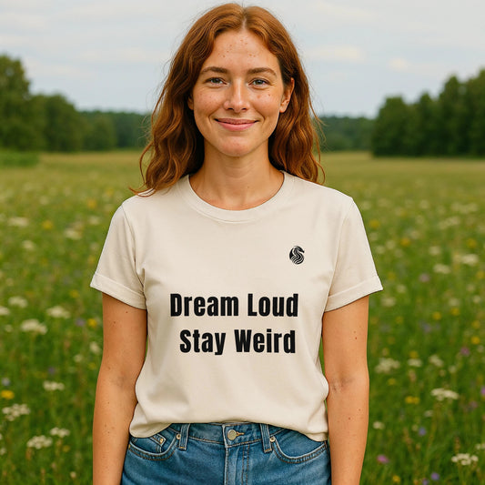 Alt Tag: Dream Loud. Stay Weird % Drix Sustainable Unisex Tee en color crema, modelo al aire libre con texto “Dream Loud Stay Weird” al frente