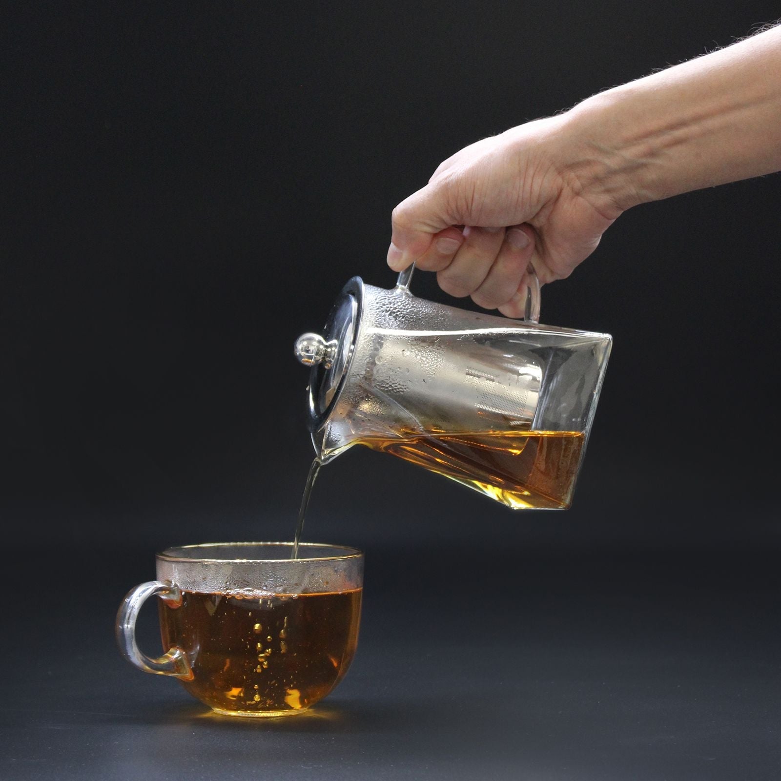 Alt Tag: Elegant Glass Infuser Teapot – Tower Shape 350ML pouring brewed tea into glass cup, clear glass and stainless steel lid