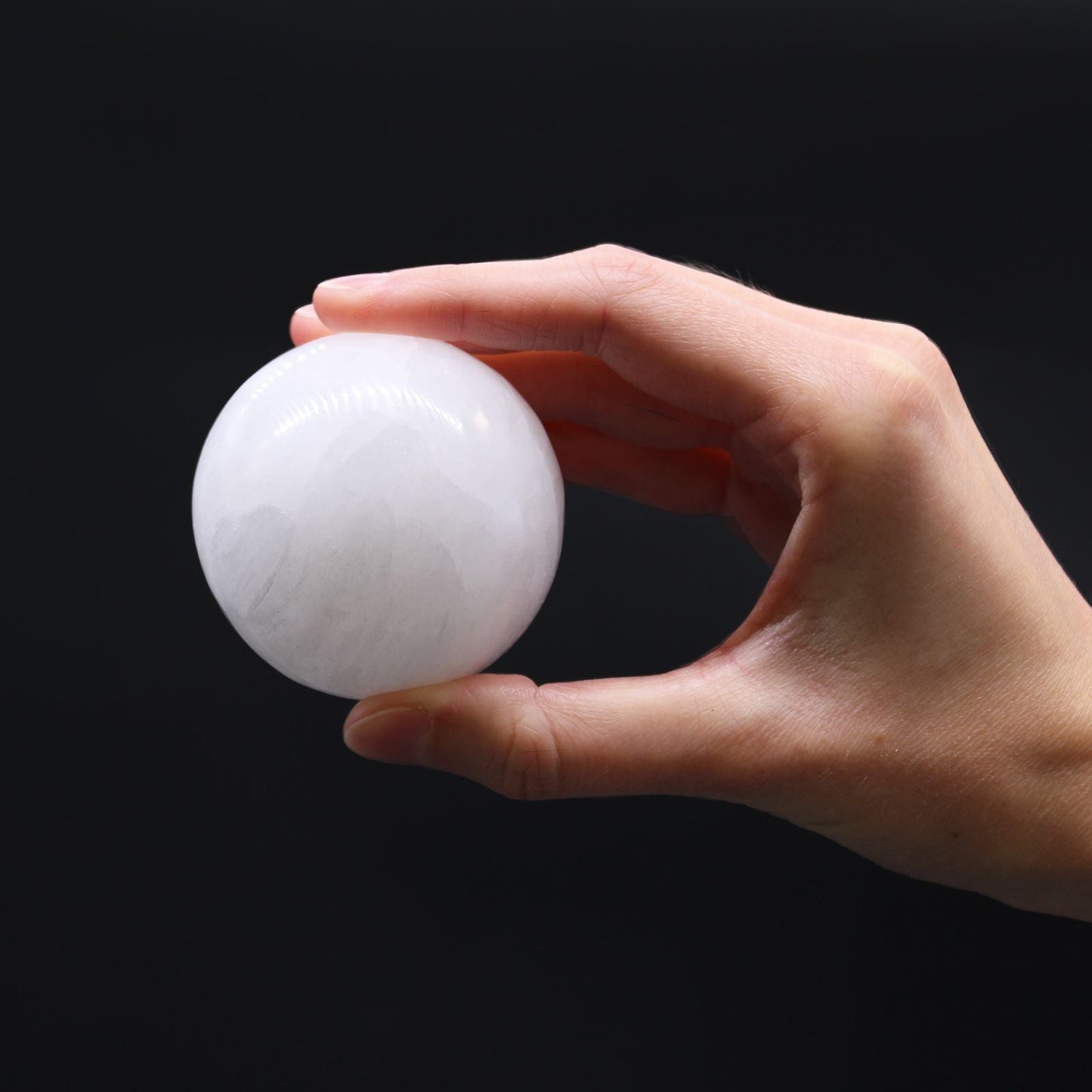 Enchanting Selenite Sphere – 5 to 6 CM held in hand, polished white selenite crystal sphere on black background