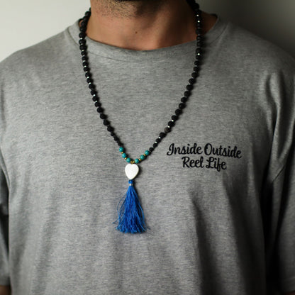 Essence of the Volcano Necklace – Calming Influence black lava stone bead necklace with turquoise accents, white heart charm and blue tassel