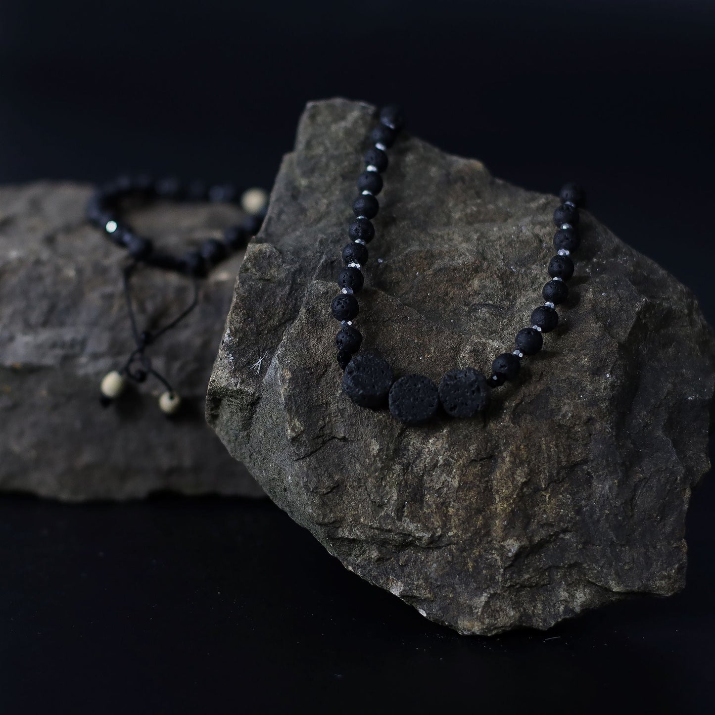Essence of the Volcano-halsband – Halsbandet Connection to Nature med svarta lavastenpärlor på naturlig klippbakgrund