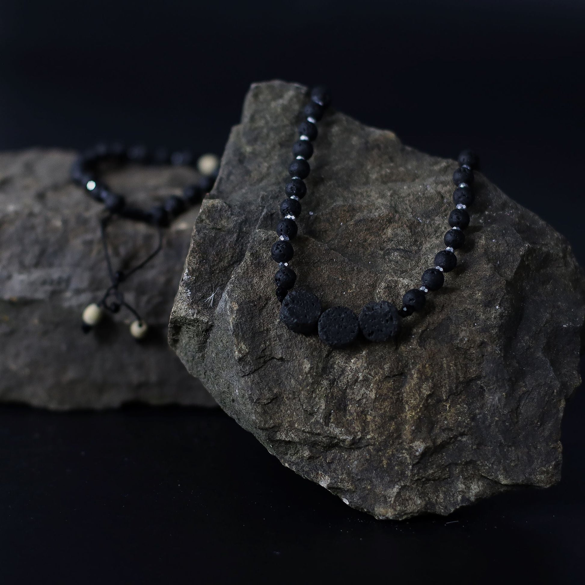 Essence of the Volcano-halsband – Halsbandet Connection to Nature med svarta lavastenpärlor på naturlig klippbakgrund