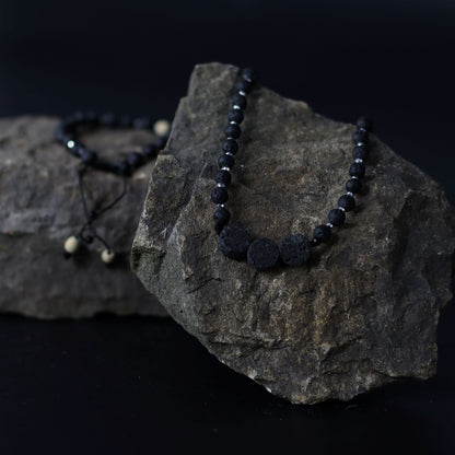 Essence of the Volcano-halsband – Halsbandet Connection to Nature med svarta lavastenpärlor på naturlig klippbakgrund