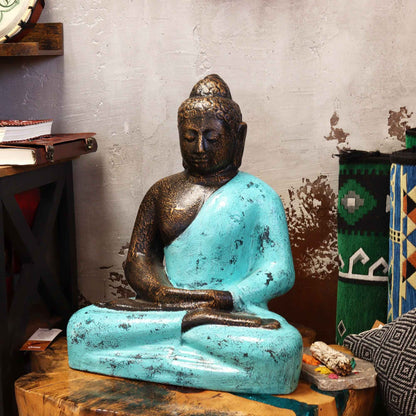 Alt Tag: Buddha-staty i fibercement – 0,5 m sittande Buddha-staty med turkos kåpa och bronsfinish på ett träbord inomhus
