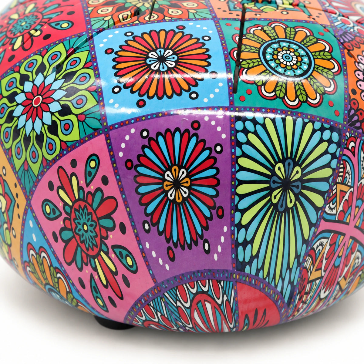Detail of purple, turquoise and green floral panels across the steel tongue drum's glossy curved side.