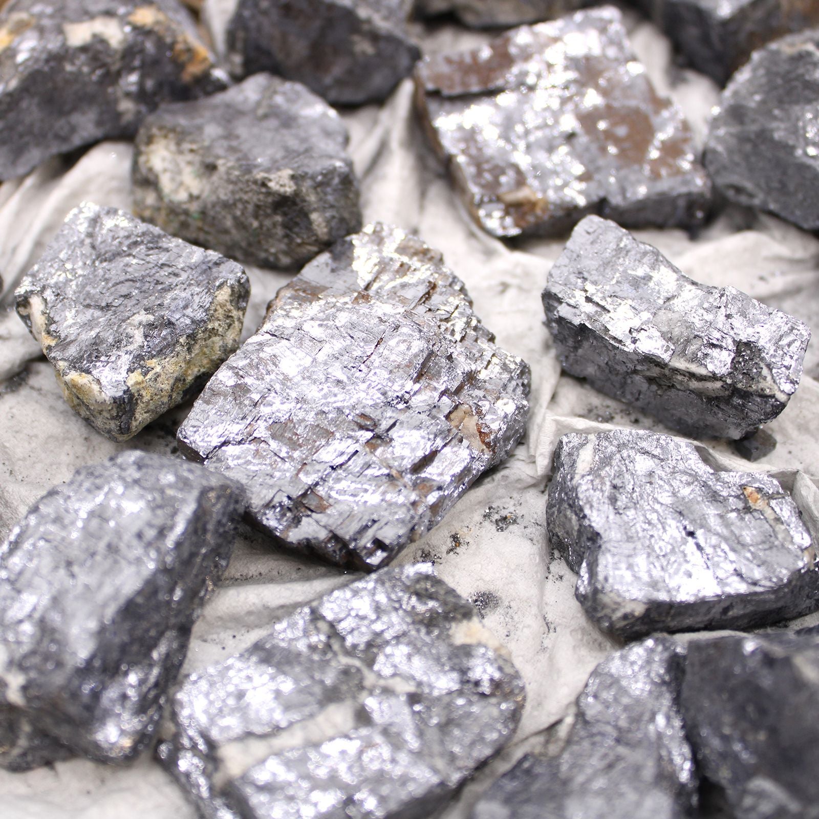 Alt Tag: Galena Rare Mineral Specimens – Approx 80 Pieces, primer plano de cristales de galena plateado-gris con brillo metálico sobre superficie clara