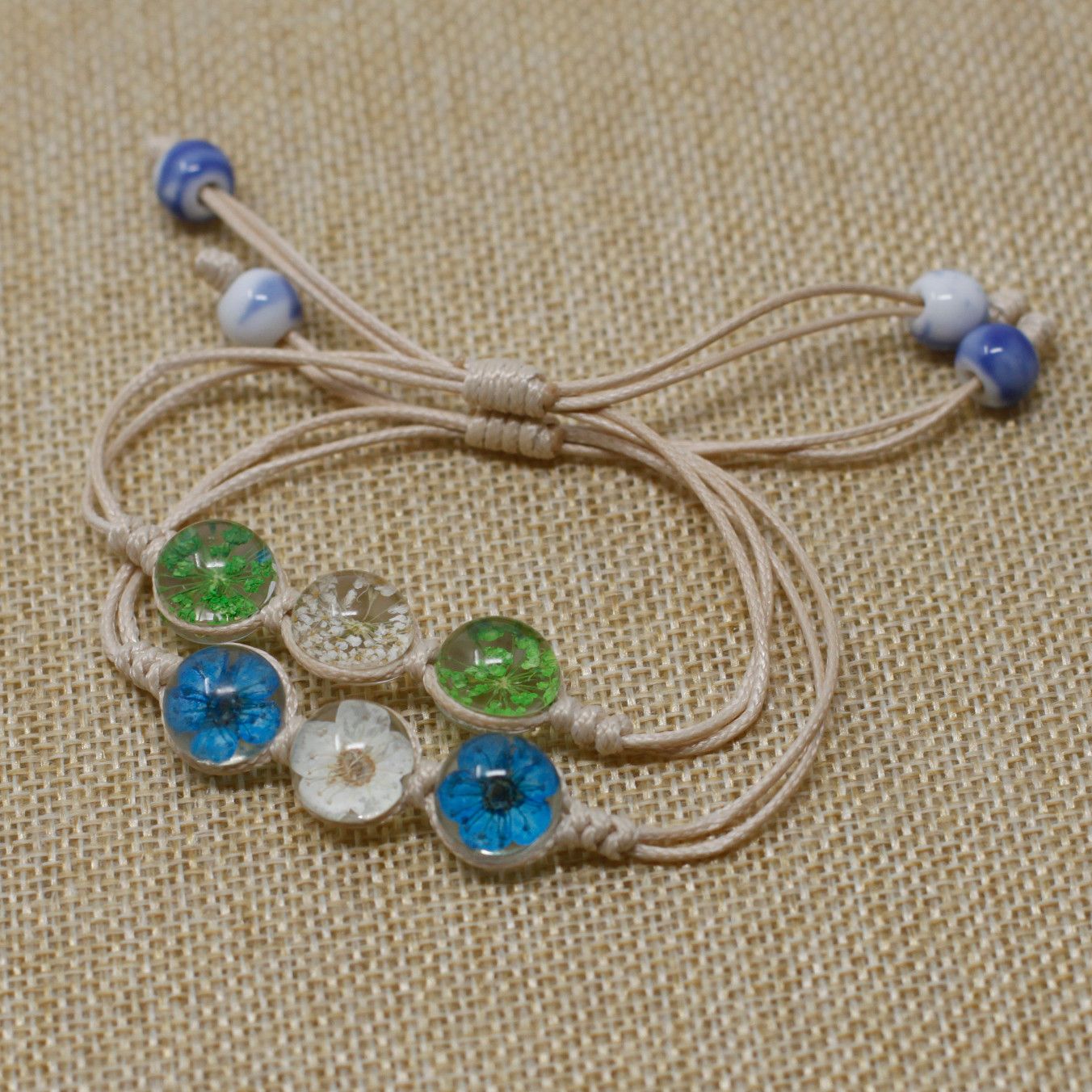 Glass & Floral Bracelet – Tri-Flower Design, pulsera ajustable con cordón beige y dijes circulares de vidrio con flores reales en azul, verde y blanco