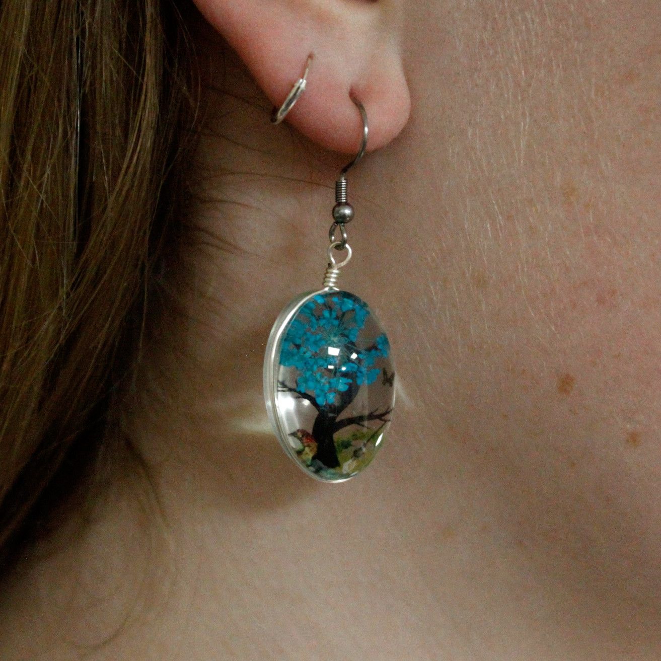 Alt Tag: Glass & Flower Tree of Life Jewellery – Green pressed flower glass drop earring worn on ear, nature-inspired green floral jewelry