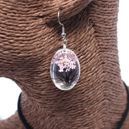 Glass & Flowers Jewelry – Tree of Life, Pink earring with pressed pink flowers encased in oval glass pendant, hanging on display bust