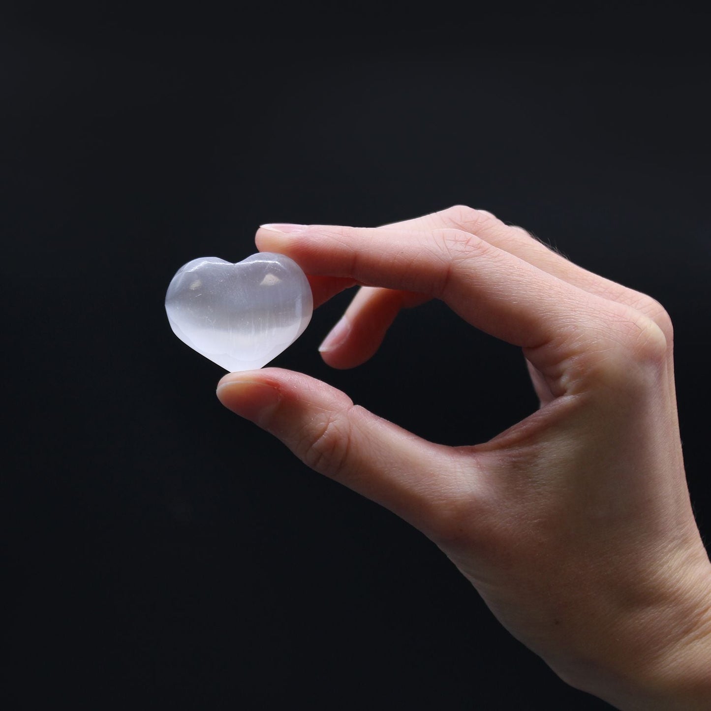 Glowing Selenite Heart – 3-4 CM heart-shaped selenite crystal held in hand, smooth translucent stone from Morocco