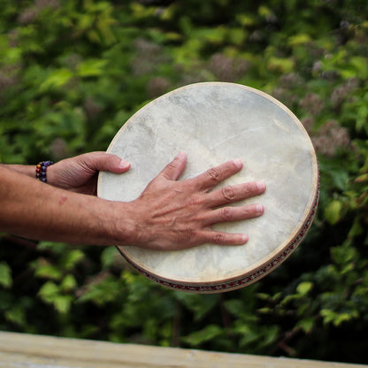 Goatskin Harmonizing Ocean Drum – 30 CM goatskin frame drum being played by hands outdoors, natural hide head close-up