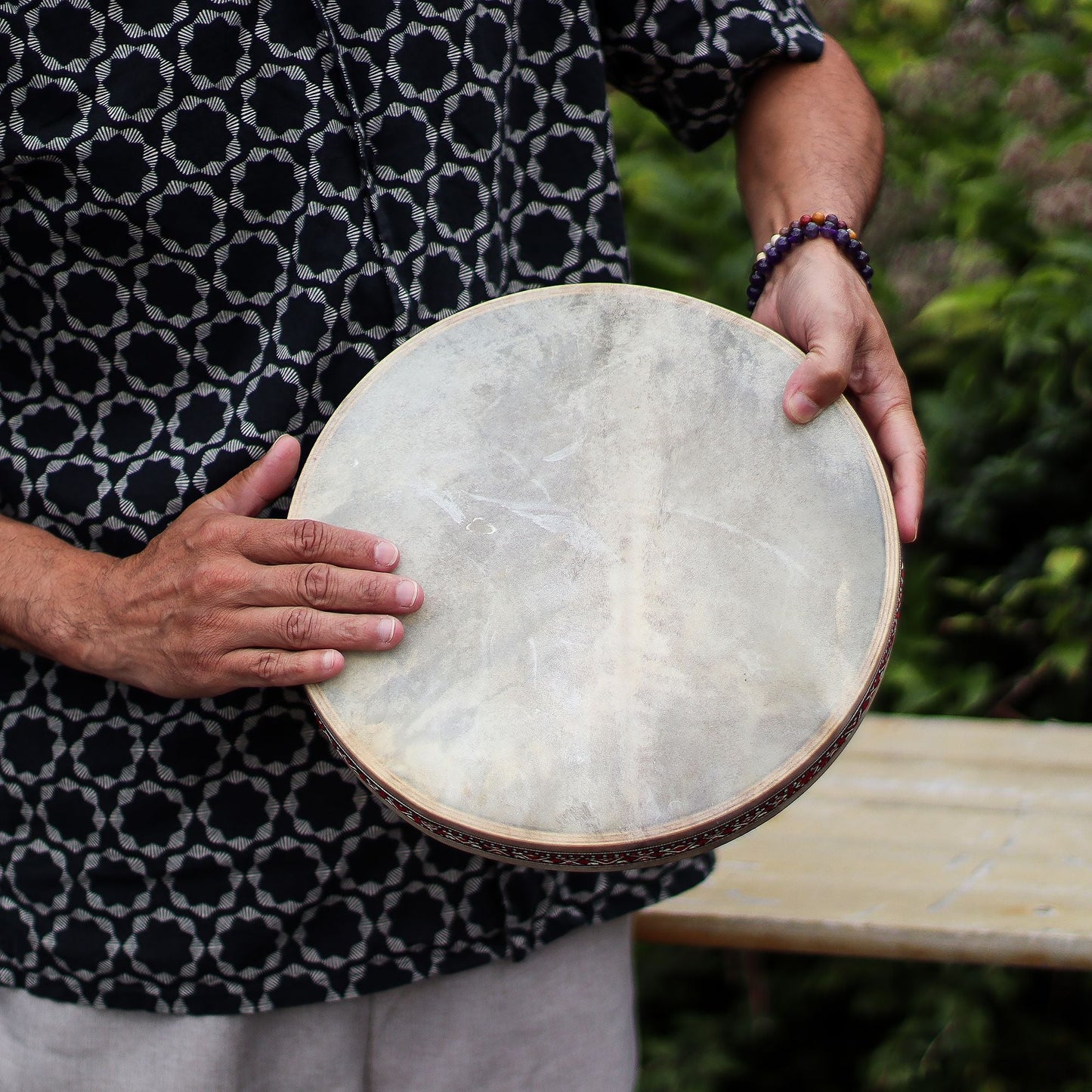 Alt Tag: Goatskin Harmonizing Ocean Drum – 30 CM en manos, tambor redondo de piel natural con aro decorado, foto en exterior