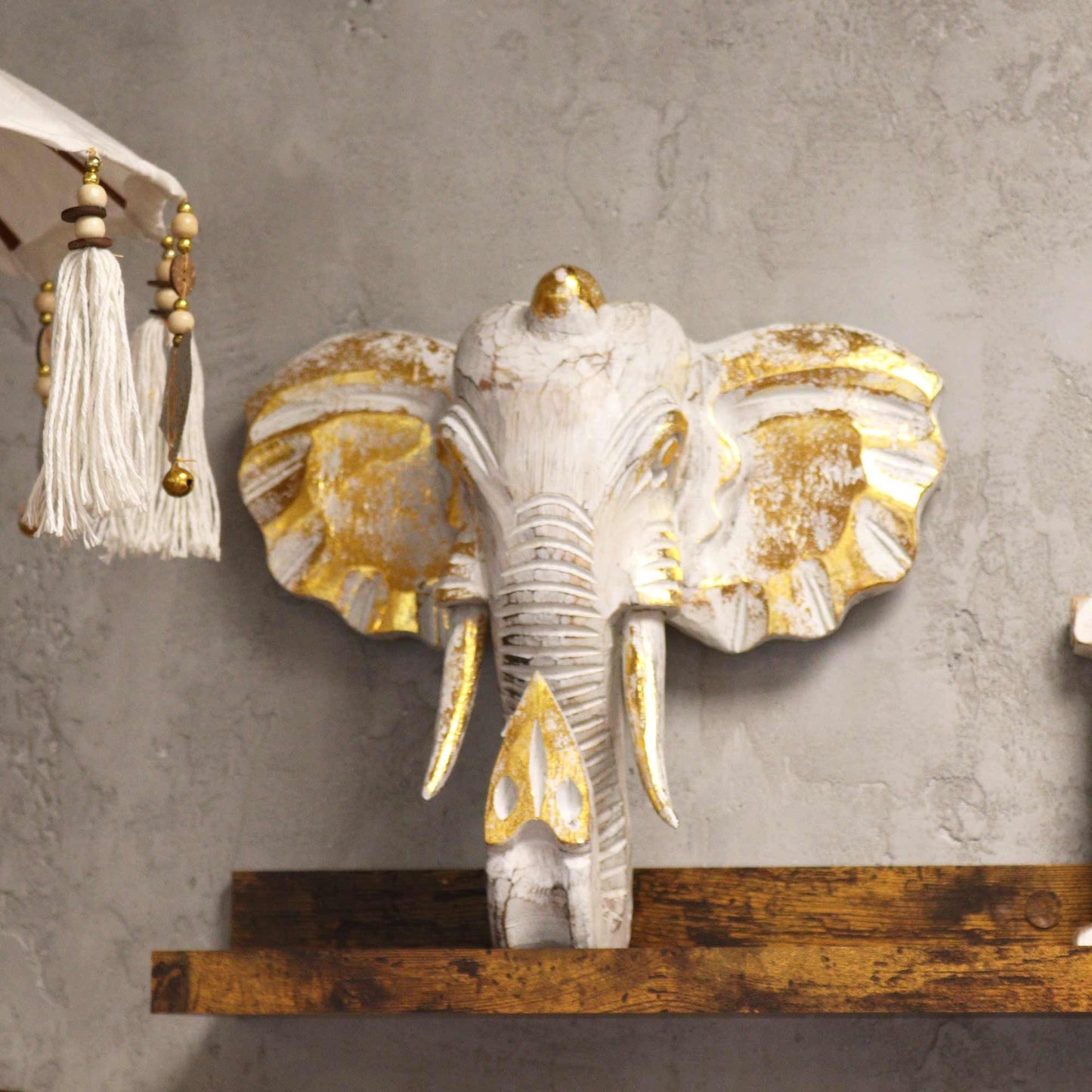Cabeza de elefante Gold & Whitewash – decoración de pared 29x26 CM en madera de Albasia con detalles dorados y acabado whitewash, montada en pared gris