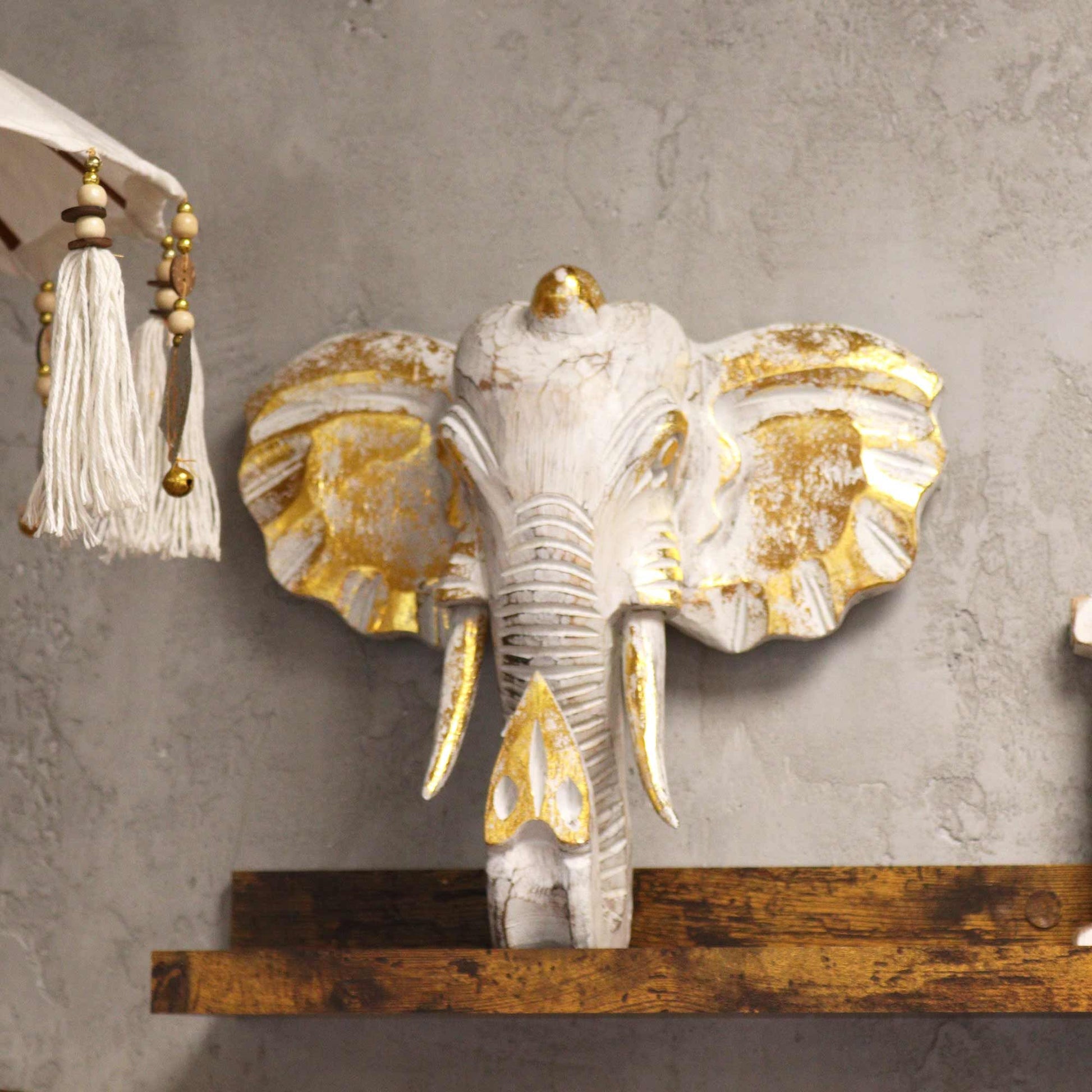 Cabeza de elefante Gold & Whitewash – decoración de pared 29x26 CM en madera de Albasia con detalles dorados y acabado whitewash, montada en pared gris