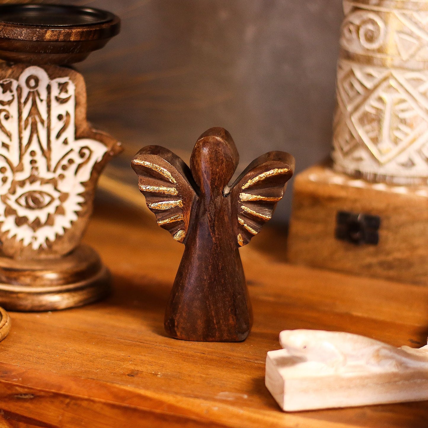 Alt Tag: Ángel de madera de mango tallado a mano – decoración de alas doradas, pequeña figura de ángel de madera con alas pintadas en dorado sobre una mesa rústica