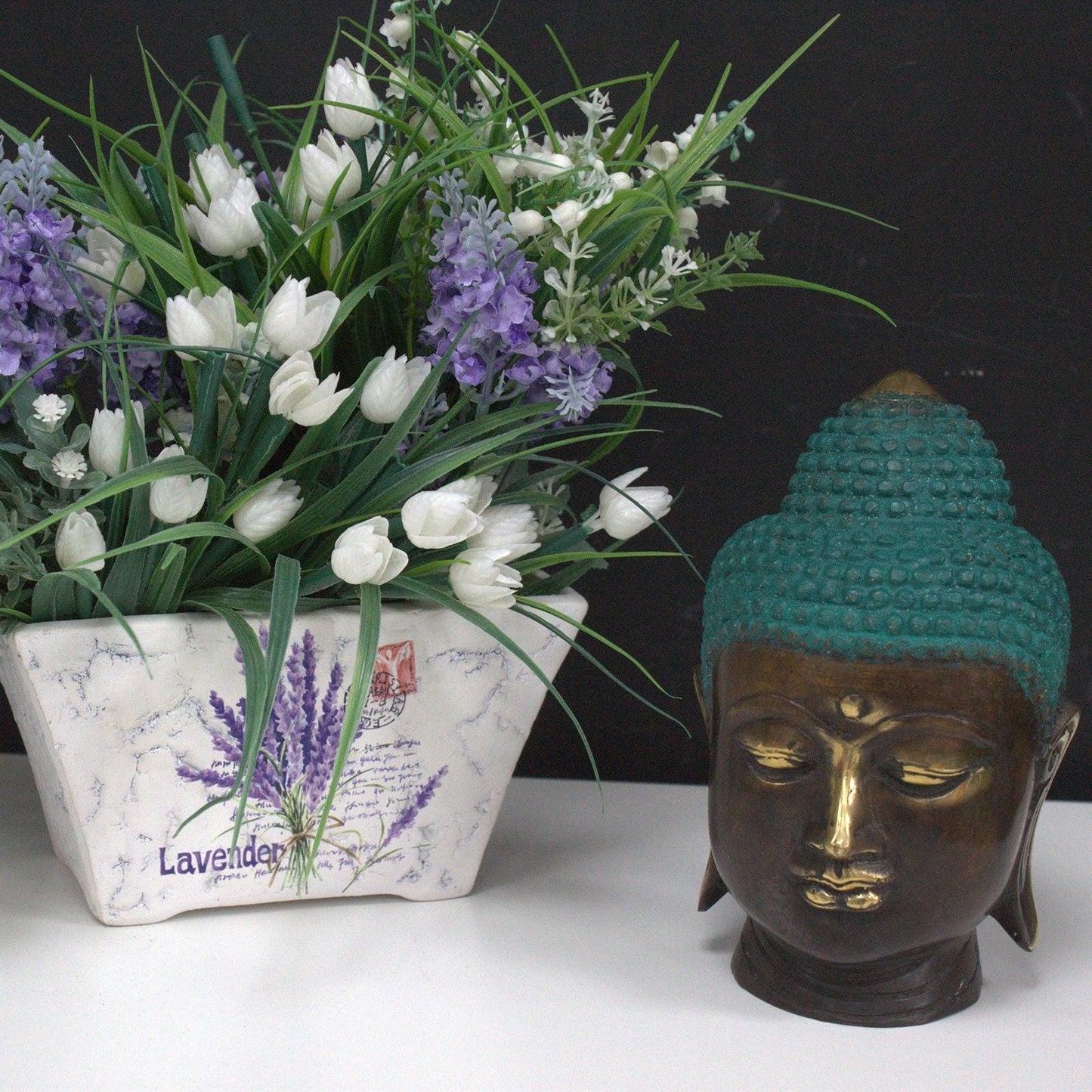 Cabeza de Buda de latón hecha a mano – 15x7x6 CM como decoración de mesa junto a flores blancas y moradas en maceta de cerámica