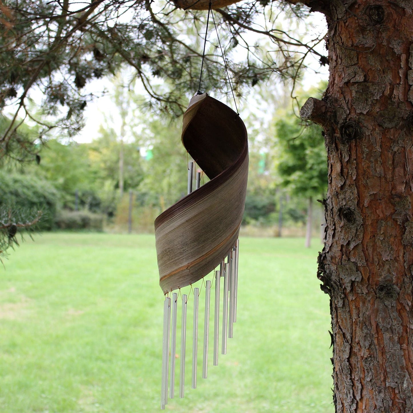 Handmade Coconut Leaf Wind Chimes – 50x13 CM hanging on a tree branch outdoors, coconut leaf wrap with metal chime tubes