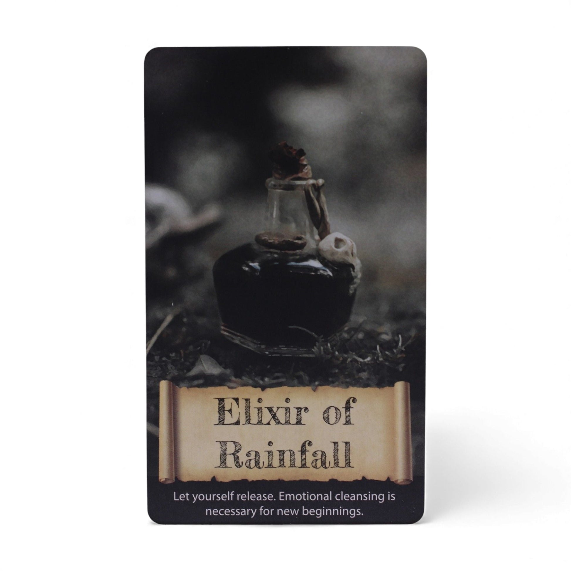 Alt Tag: Harmonizing Energy Oracle Cards – Insightful Deck card “Elixir of Rainfall” with dark glass bottle and scroll-style title