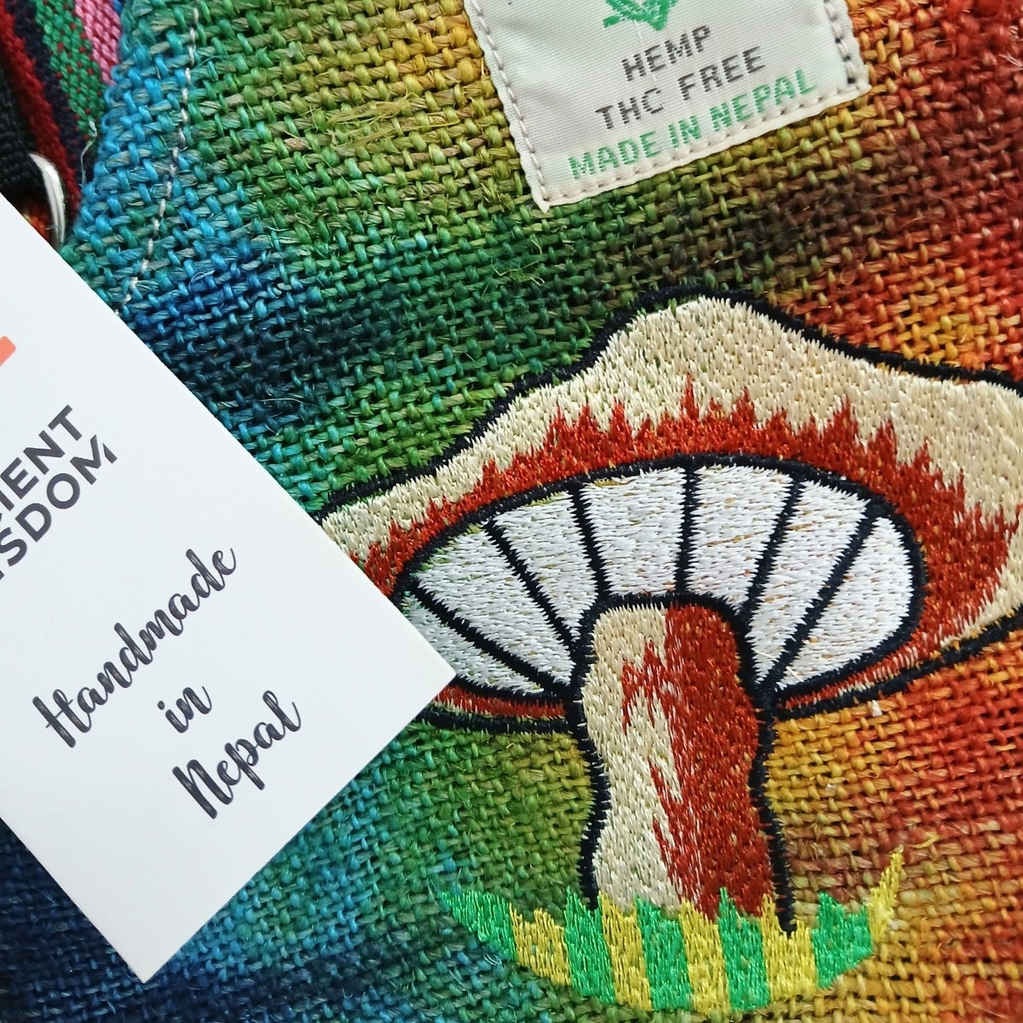 Broderad party bag i hampa & bomull – Orange Mushrooms närbild av orange svampbrodyr på flerfärgat hampatyg, handgjord i Nepal