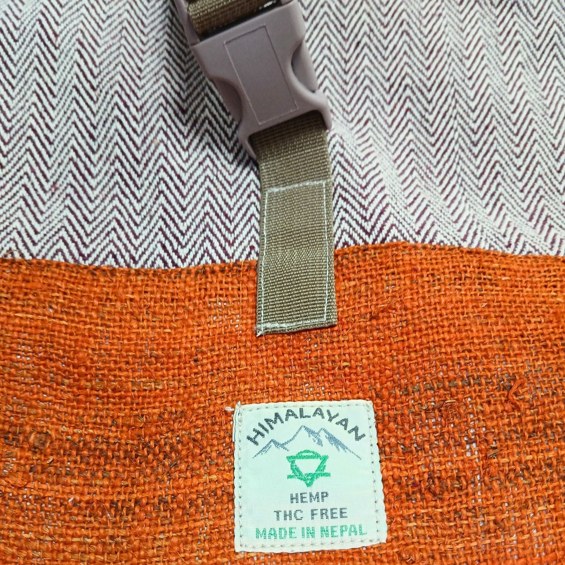Alt Tag: Hemp Trekking Rolling Backpack – Sunset Orange close-up of hemp fabric, buckle strap and Himalayan Hemp Made in Nepal label