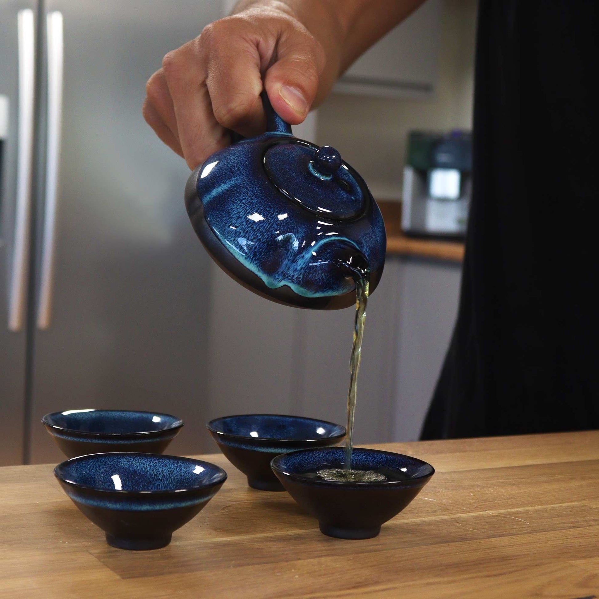 Herbal Blues Teapot Set – Pot & Four Cups pouring tea into matching blue glazed ceramic cups
