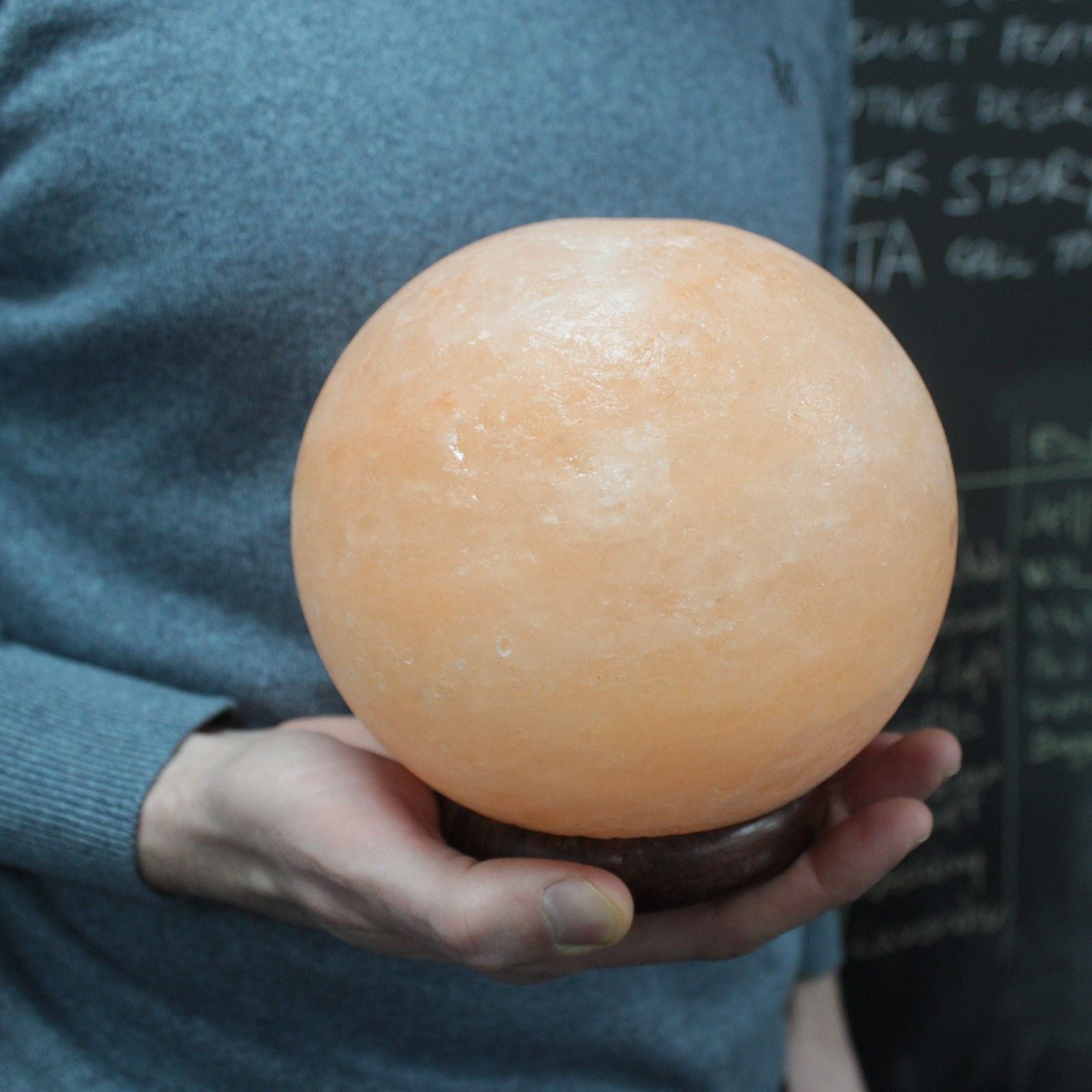 Himalayan Salt Lamp Ball – Large with Wooden Base, hand-carved spherical pink salt lamp on wooden base held in hands