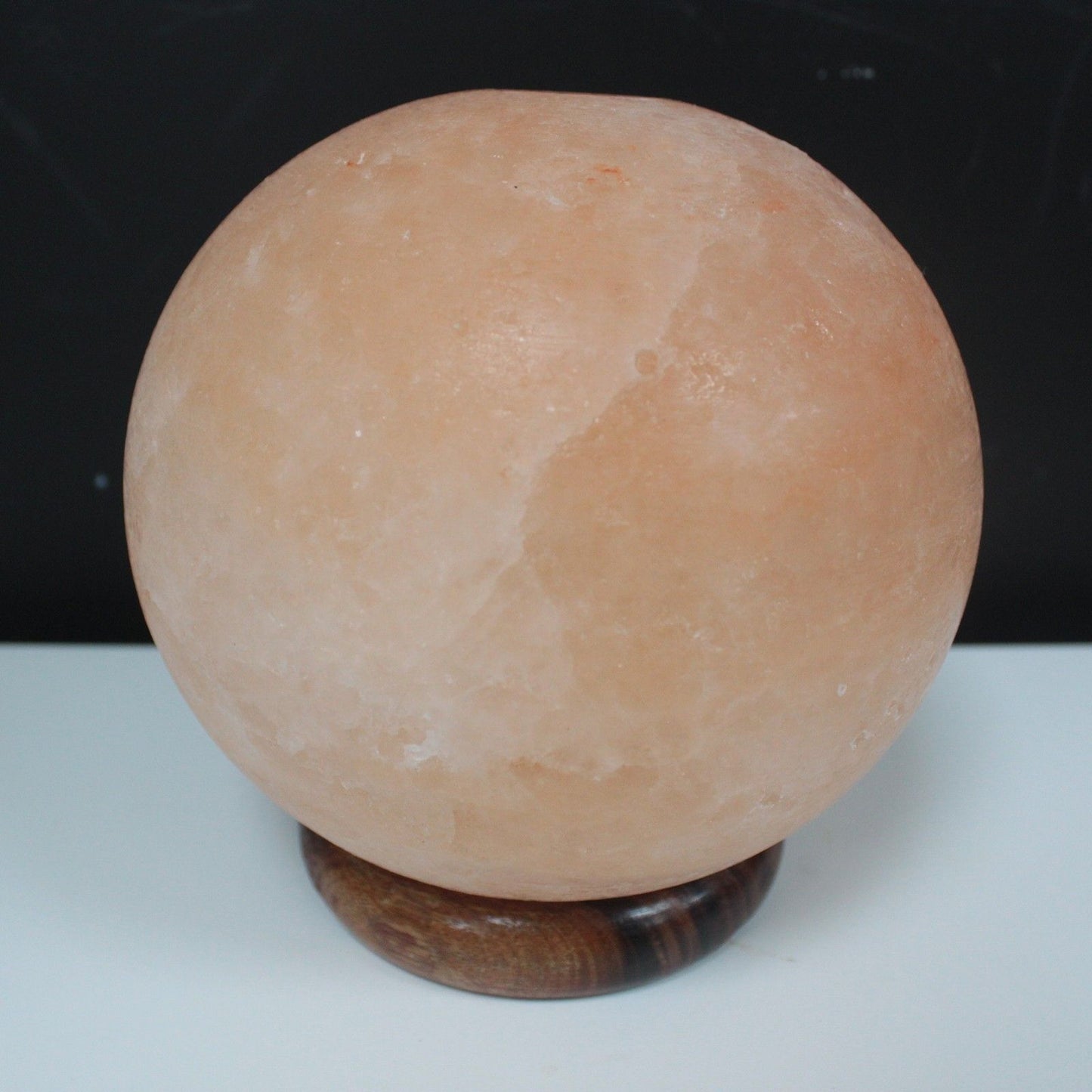 Alt Tag: Himalayan Salt Lamp Ball – Large with Wooden Base, hand-carved spherical Himalayan salt lamp on wooden base, warm amber glow