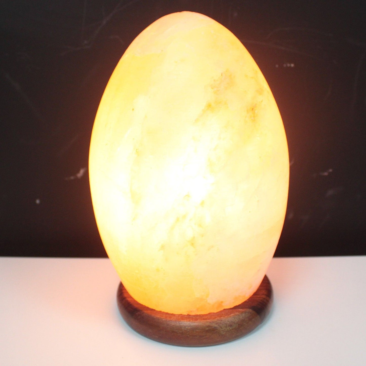 Alt Tag: Himalaya-saltlampa Egg – Äggformad rosa saltkristallampa med varm bärnstensfärgad glöd på rund träbas