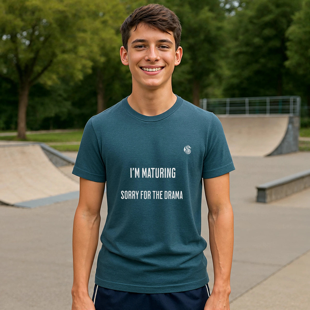 I’m Maturing Teen Sustainable Unisex Tee worn by teen in teal, front view with “I’M MATURING SORRY FOR THE DRAMA” text at skatepark