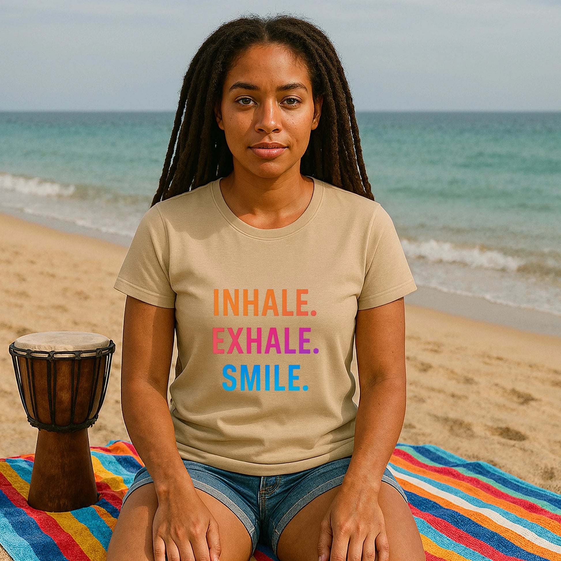 Alt Tag: Inhale Exhale Smile Mindfulness 100% Organic Cotton T-Shirt worn by woman on beach, beige tee with Inhale Exhale Smile print