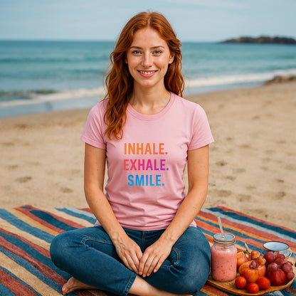 Alt Tag: Inhale Exhale Smile Mindfulness 100% Organic Cotton T-Shirt modelo mujer en playa, camiseta rosa con texto INHALE EXHALE SMILE