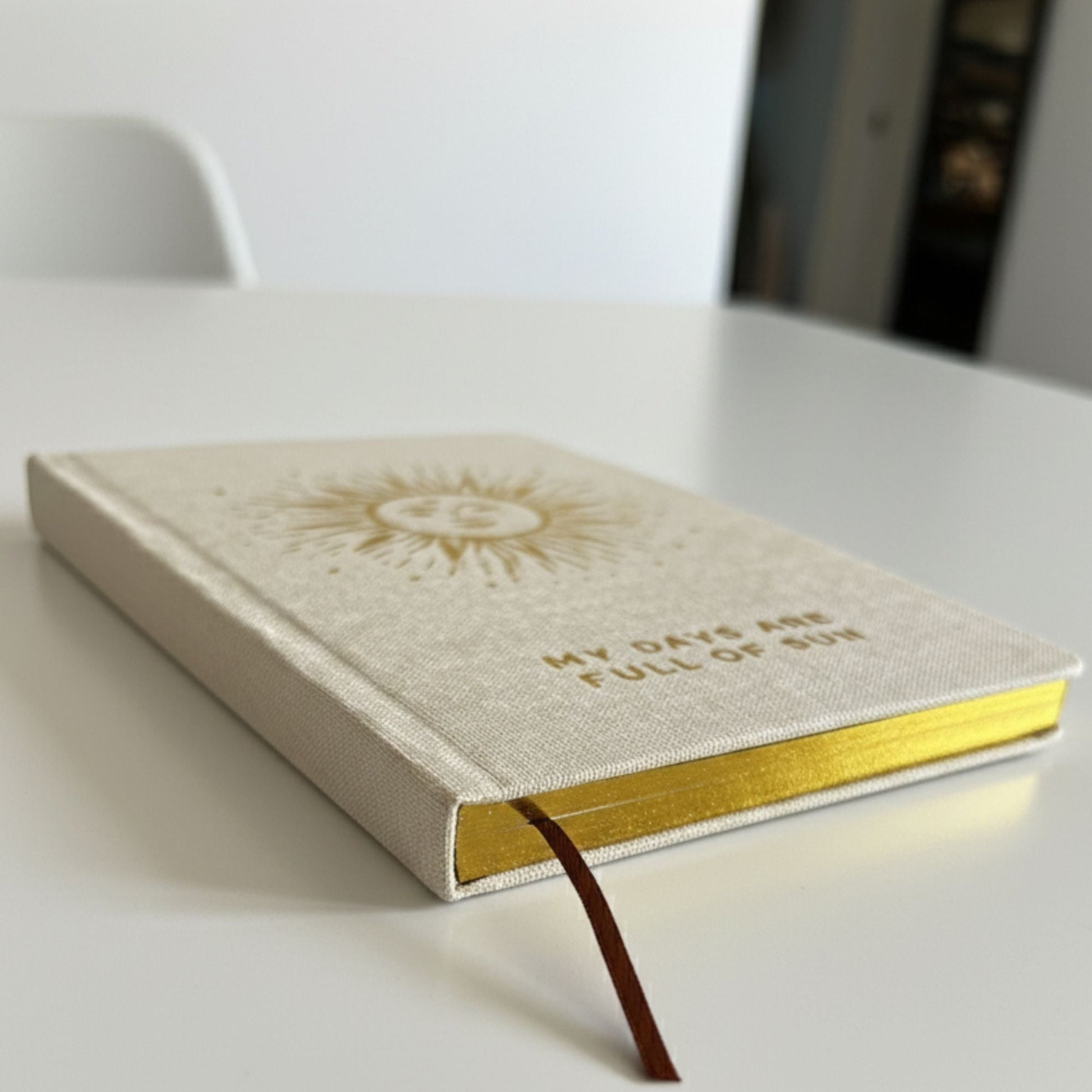 Alt Tag: Ivory Gratitude Journal with Gold Lining – 120 Pages – My Days Are Full of Sun on table, ivory cover and gold-lined edges