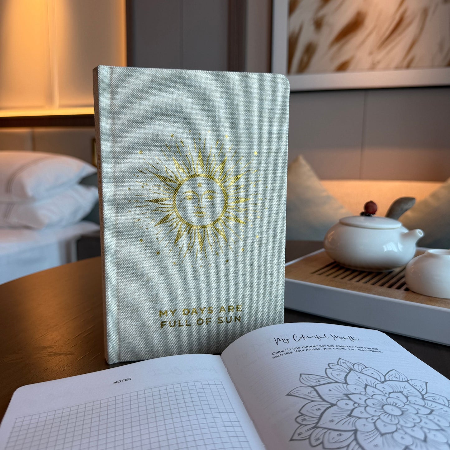 Ivory Gratitude Journal with Gold Lining – 120 Pages – My Days Are Full of Sun on desk, ivory cover with sun design, open pages