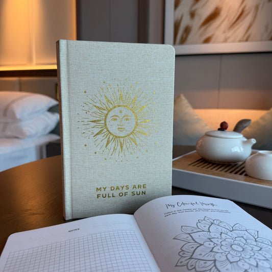 Ivory Gratitude Journal with Gold Lining – 120 Pages – My Days Are Full of Sun on desk, ivory cover with sun design, open pages