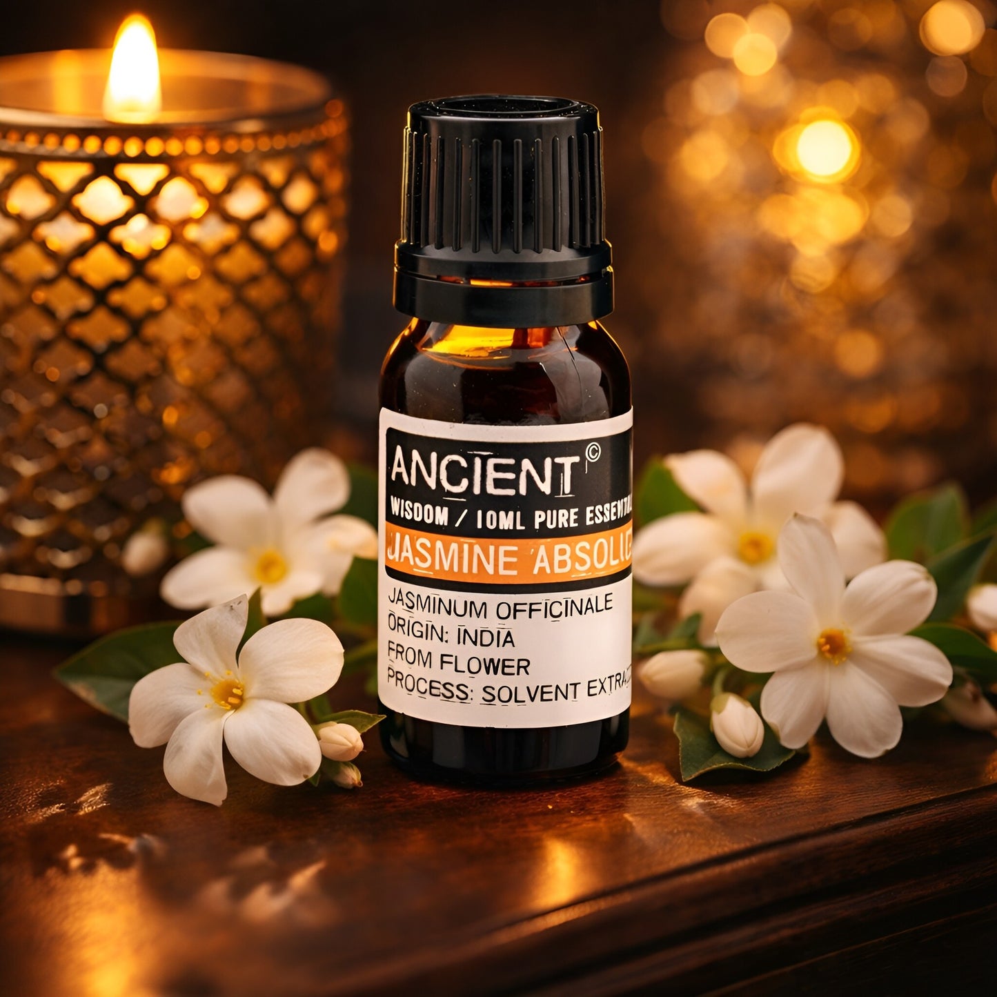 Alt Tag: Jasmine Absolute eterisk olja – 10 ML i bärnstensfärgad flaska med etiketten Jasmine Absolute, jasminblommor och ett ljus i bakgrunden