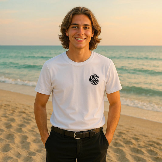 Alt Tag: Joven Dragon Premium Unisex T-Shirt blanca con logo de dragón en el pecho, modelo de pie en la playa al atardecer