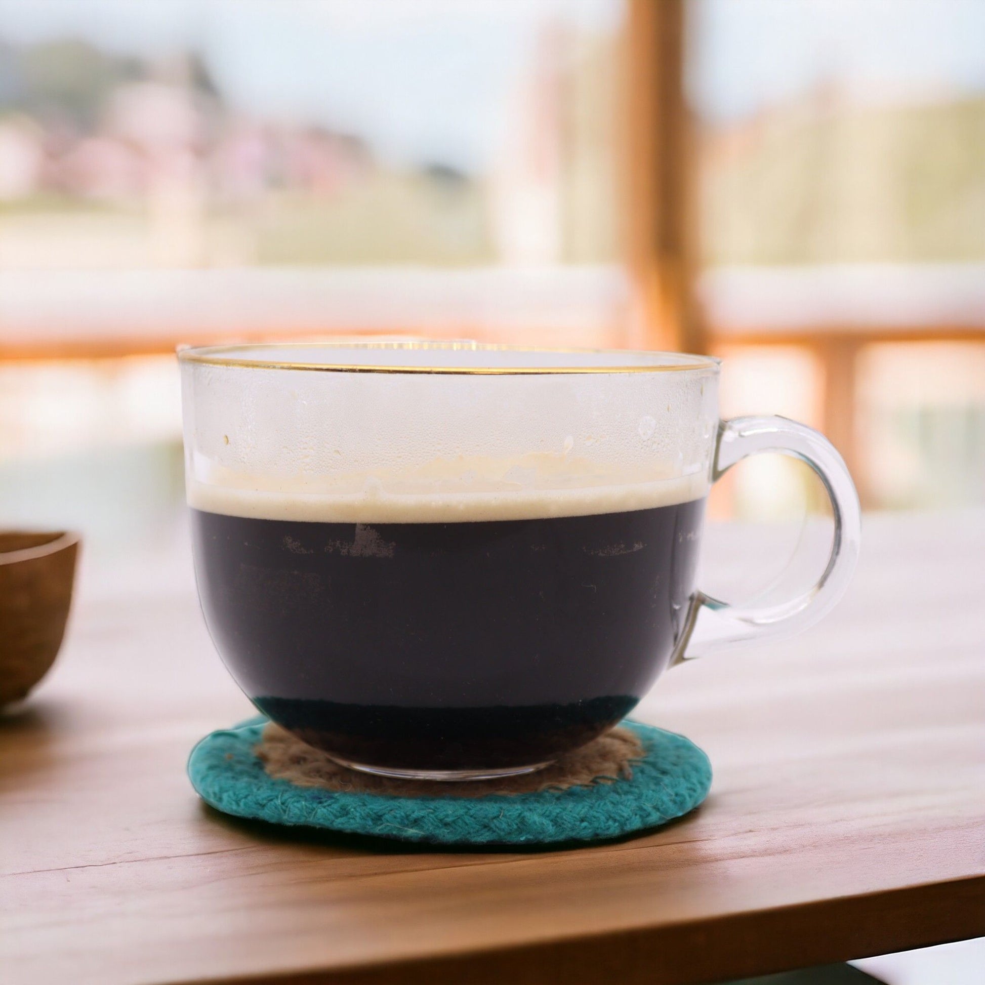 Glasunderlägg i jute & bomull – 10CM turkos kant med kaffekopp i glas på turkoskantat vävt glasunderlägg i jute och bomull