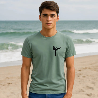 Alt Tag: Karate Kick Sustainable Unisex Tee in sage green with black karate kick silhouette, worn by model on beach