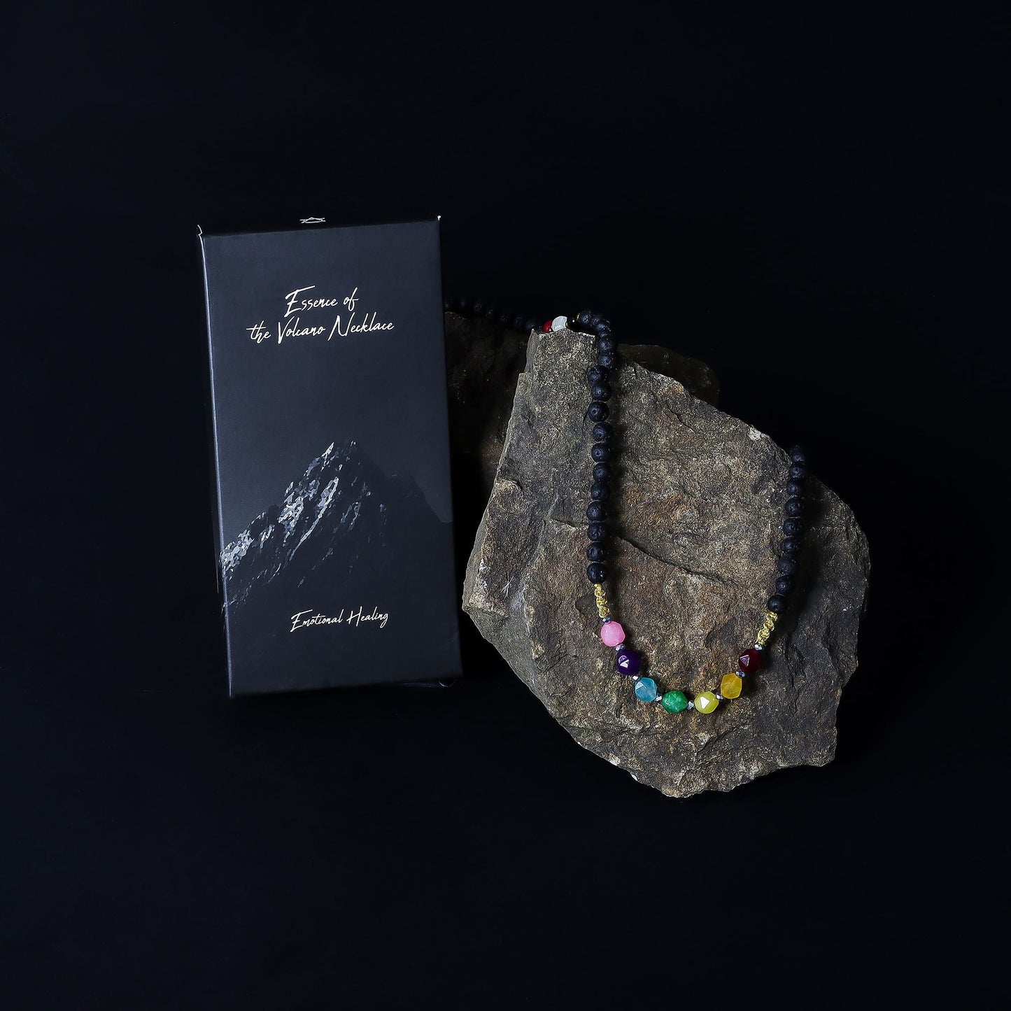 Alt Tag: Lava Stone 7-Chakra Necklace – Emotional Harmonizing with chakra crystal beads on rock, shown with black gift box