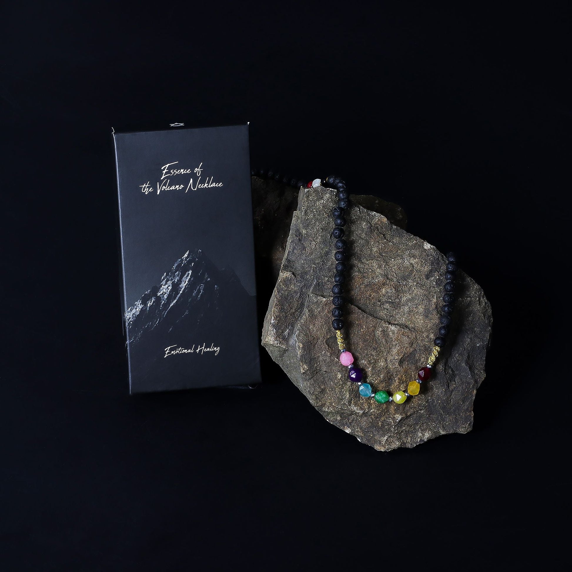 Alt Tag: Lava Stone 7-Chakra Necklace – Emotional Harmonizing with chakra crystal beads on rock, shown with black gift box