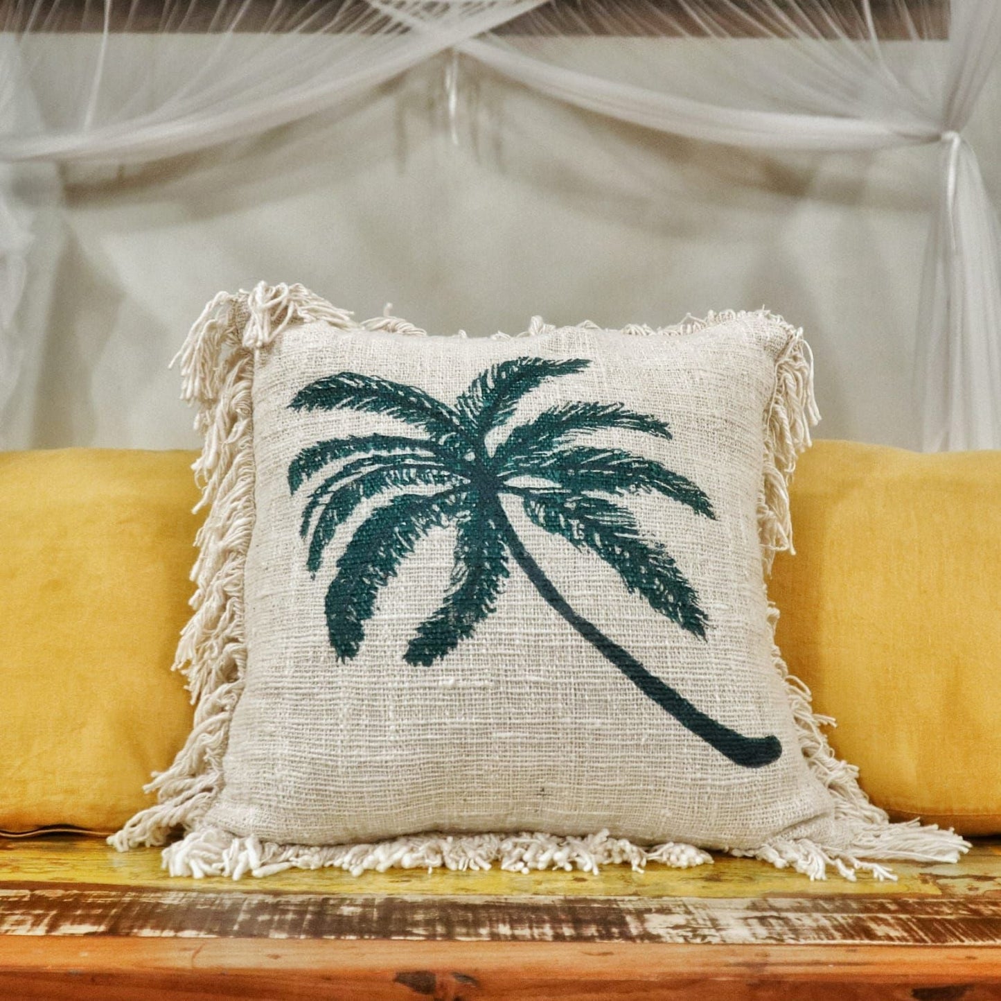 Alt Tag: Linen Palm Tree Cushion – 45x45 CM square linen-cotton cushion cover with palm tree print and fringed edges on sofa