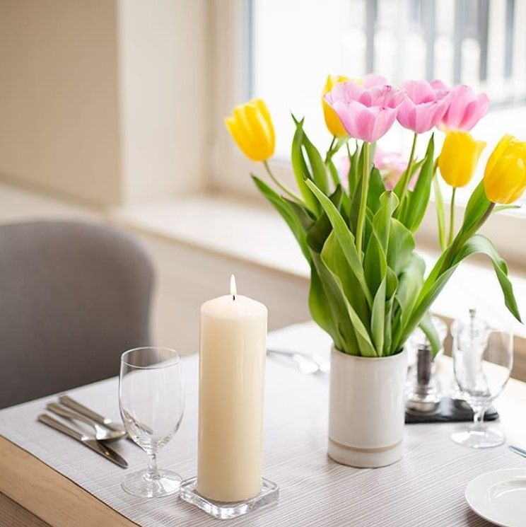 Luxurious Parafin Pillar Candle – 60x100MM Red pillar candle styled on dining table with glassware and tulips in vase