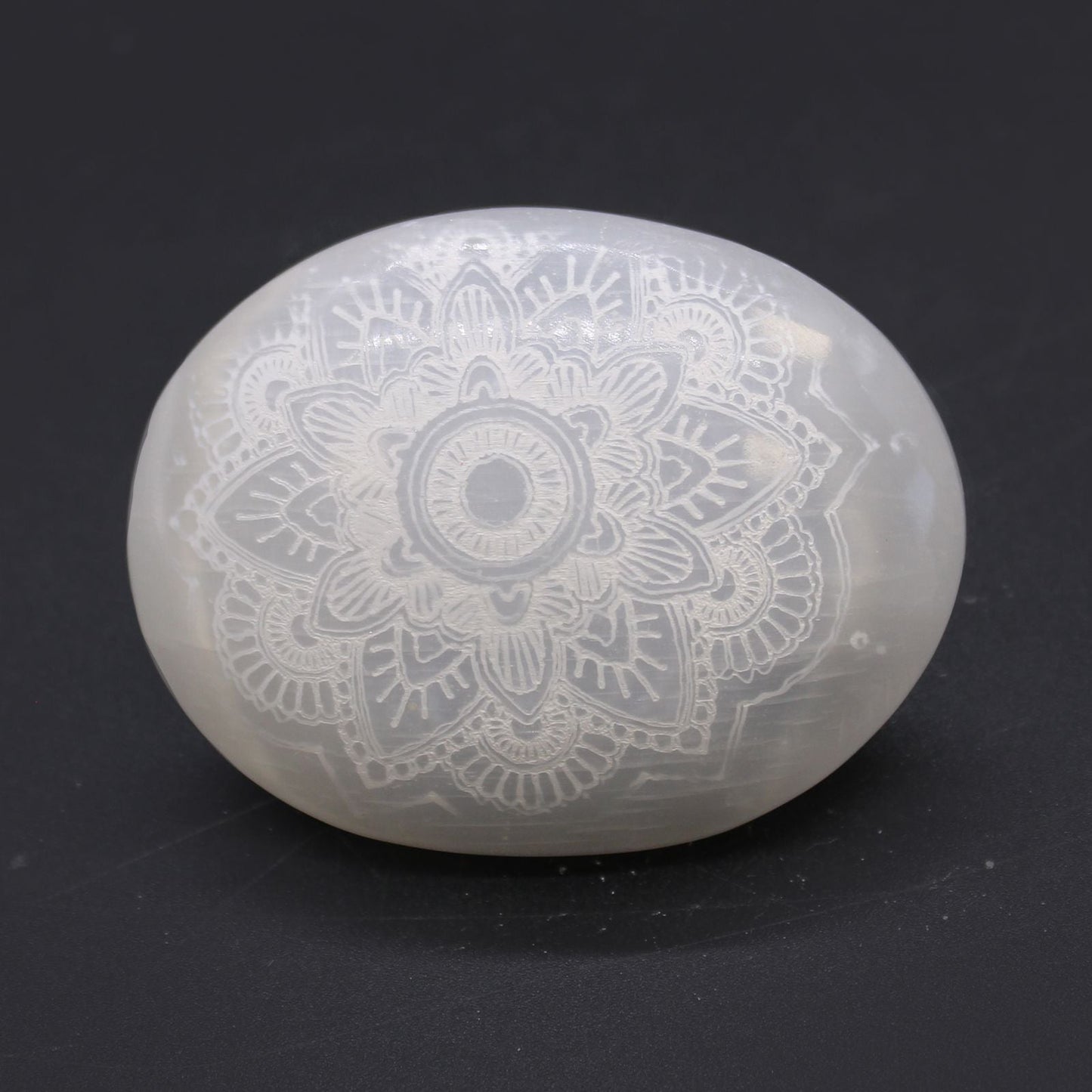 Mandala-Engraved Selenite Stone – 7x5x2 CM, white palm stone with mandala engraving on dark background