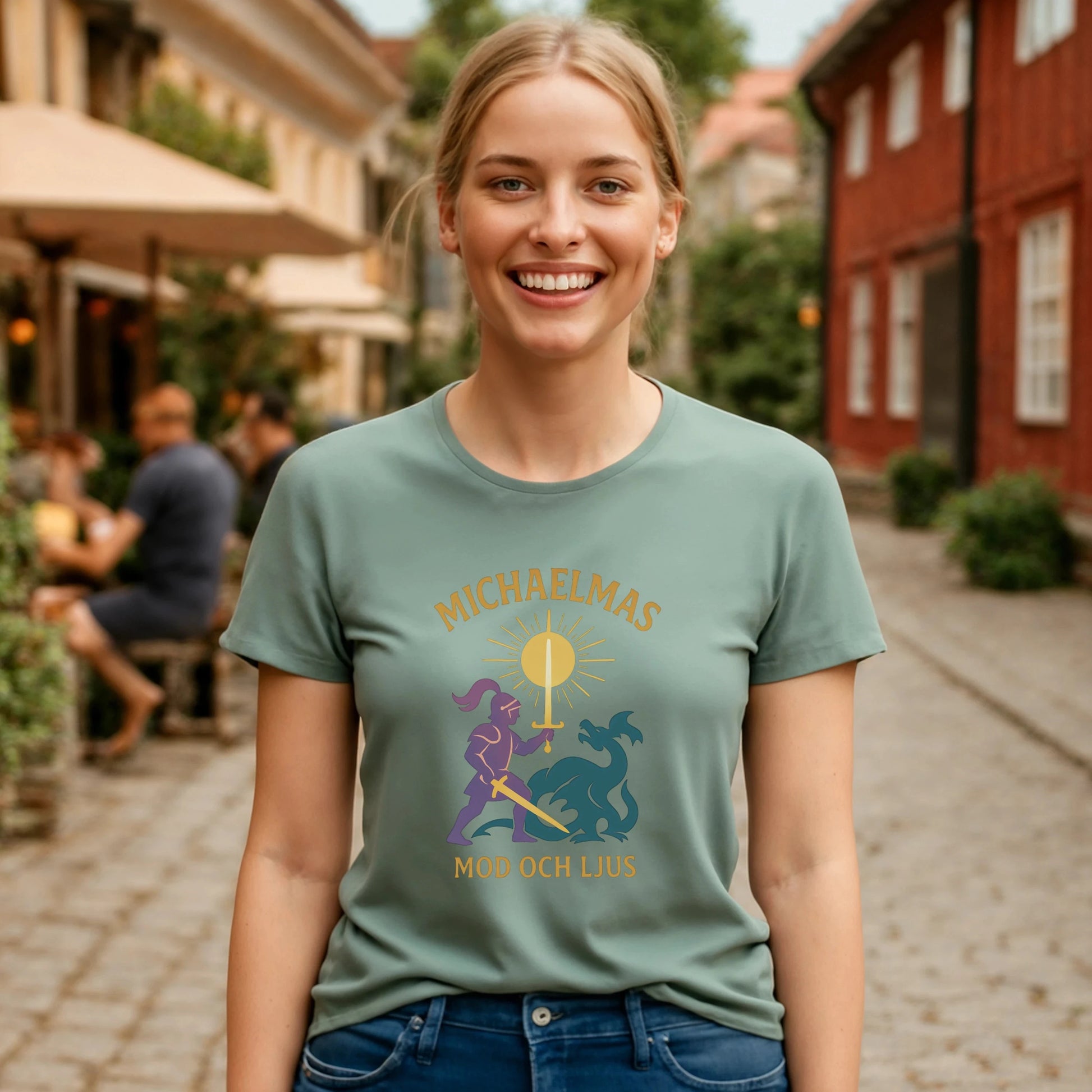 Michaelmas Mod Ljus 100% Organic Cotton T-Shirt worn by smiling woman on city street, sage green graphic tee with Michaelmas design
