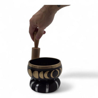 Alt Tag: Moon Phase Singing Bowl Set – Black 10.7 CM with gold moon phase design, matte black finish, hand holding wooden mallet