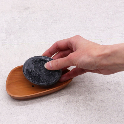 Naseberry Wood Mahogany Soap Dish – 12x6 CM with drainage slot, pebble shape wooden holder with black soap bar in hand