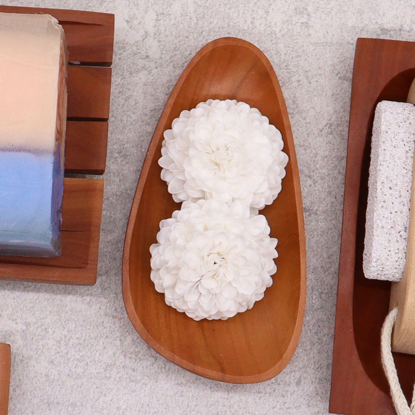 Alt Tag: Naseberry Wood Mahogany Soap Dish – 12x6 CM, handcrafted pebble-shaped wooden soap dish with drainage slots, styled with white flowers