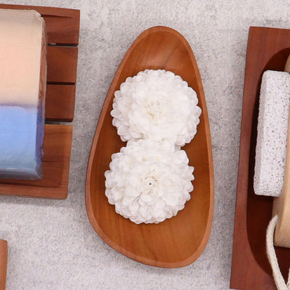 Alt Tag: Naseberry Wood Mahogany Soap Dish – 12x6 CM, handcrafted pebble-shaped wooden soap dish with drainage slots, styled with white flowers